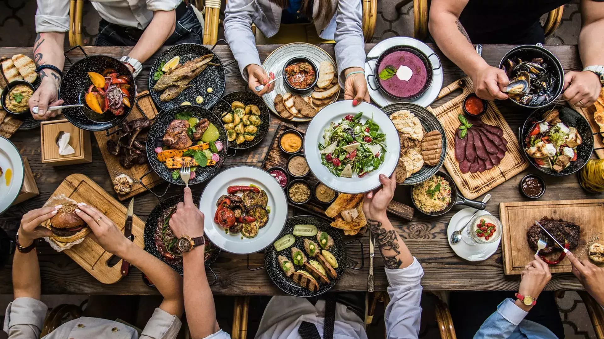 People sitting at a dining table, sharing food.