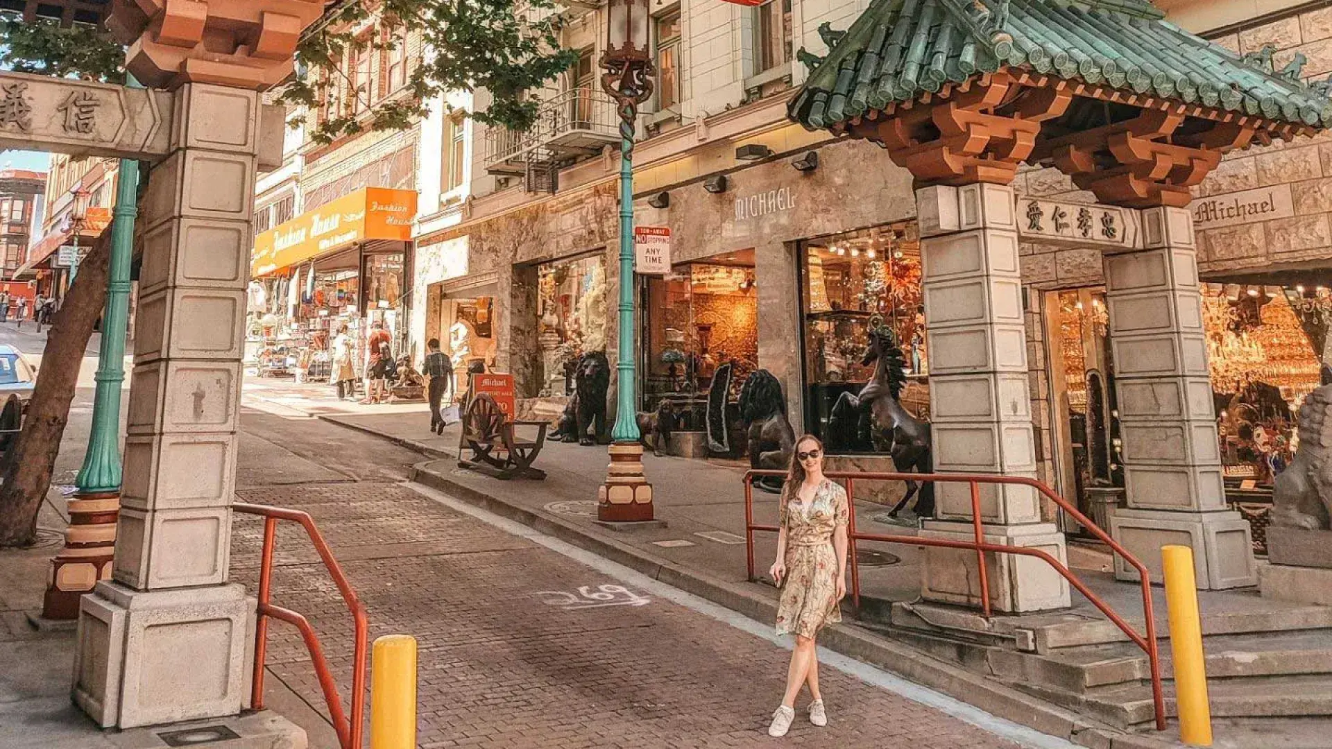 Uma mulher posa em frente a um portão ornamentado que marca a entrada do Chinatown de São Francisco.