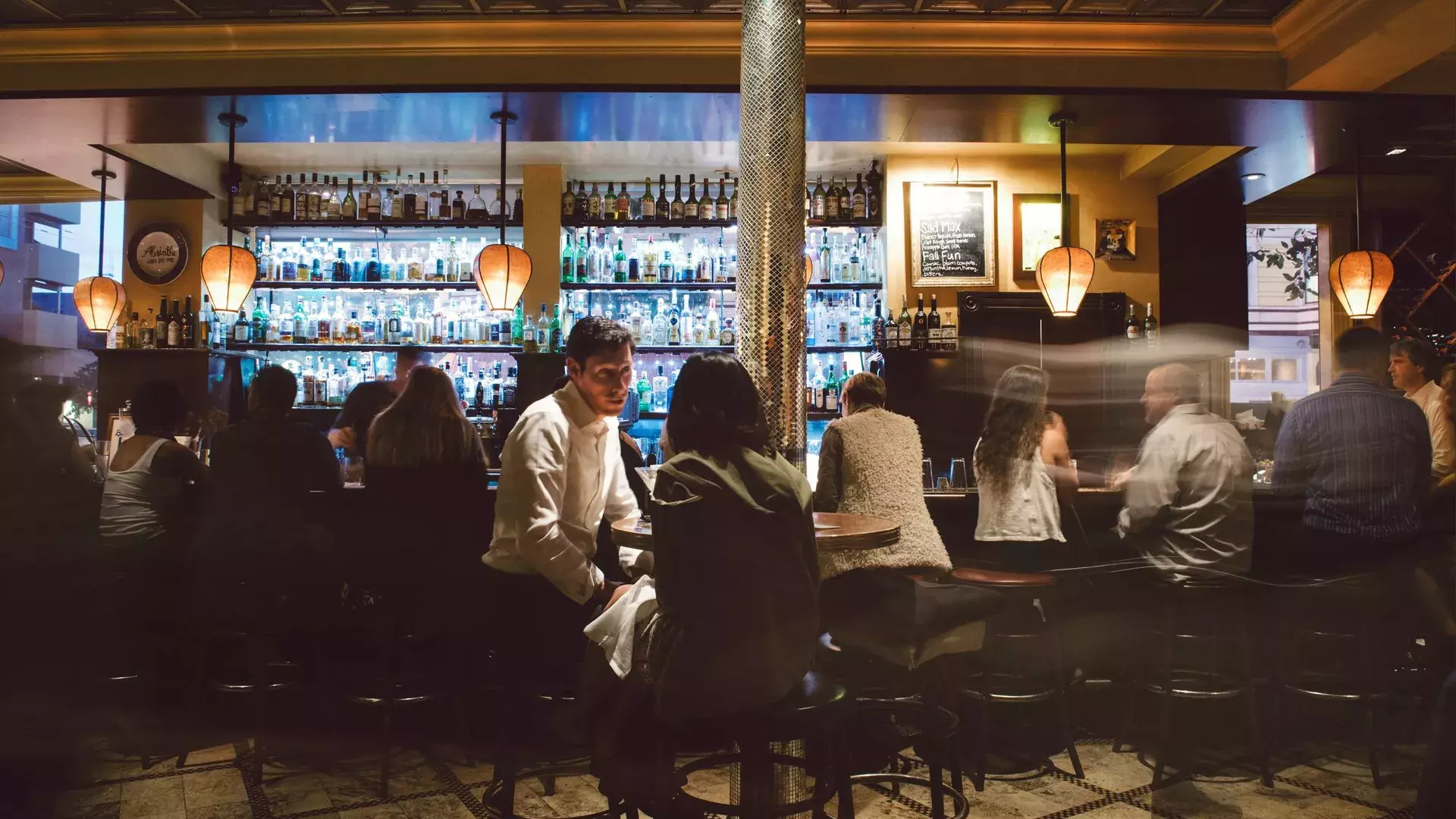 A couple share drinks at a busy San Francisco bar.