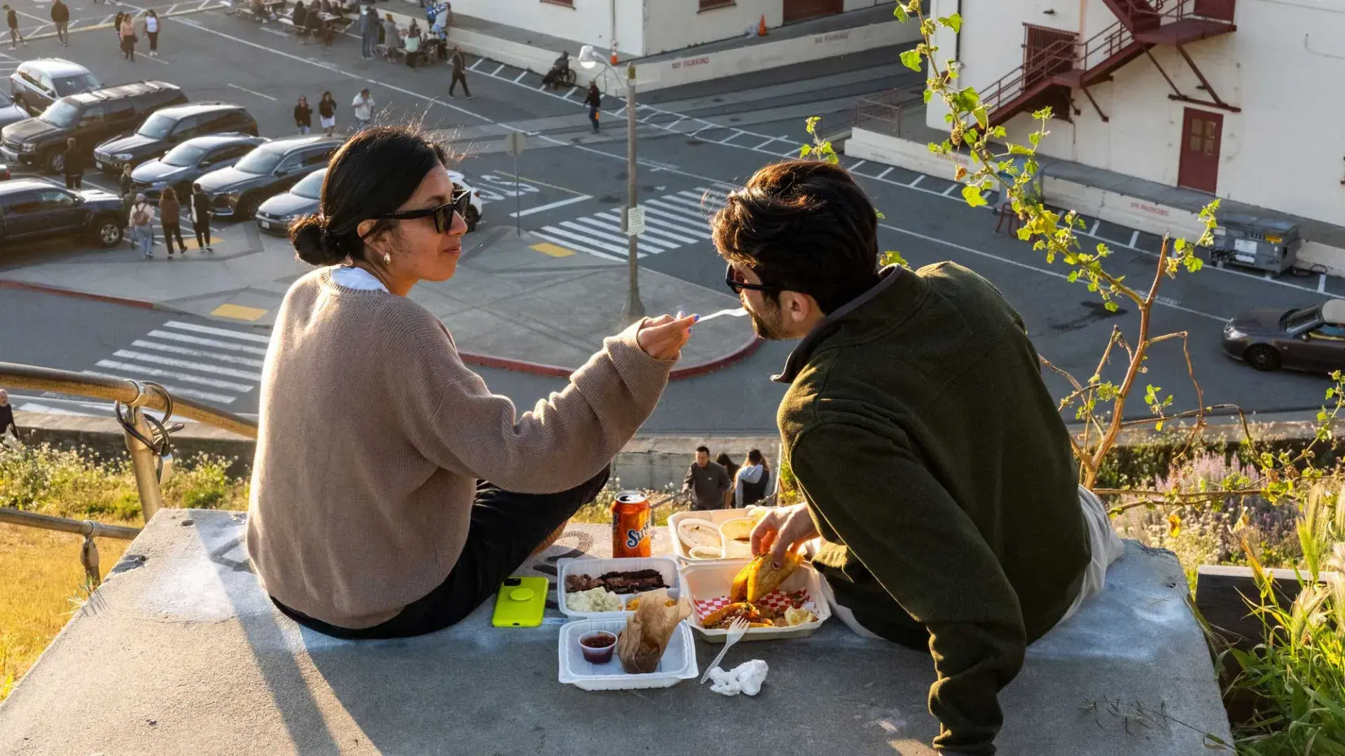 A couple dines al fresco at Fort Mason Center in San Francisco. The woman feeds her companion a taste of food.