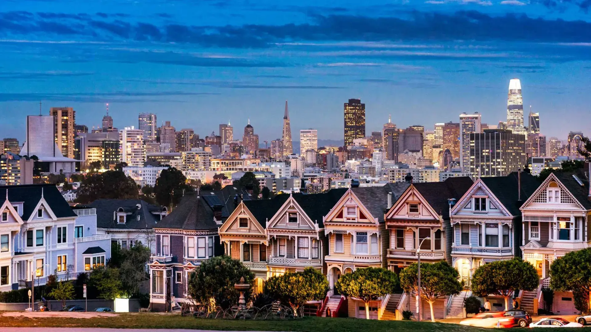 The famous Painted Ladies of Alamo Square are pictured before the San Francisco skyline at twilight.