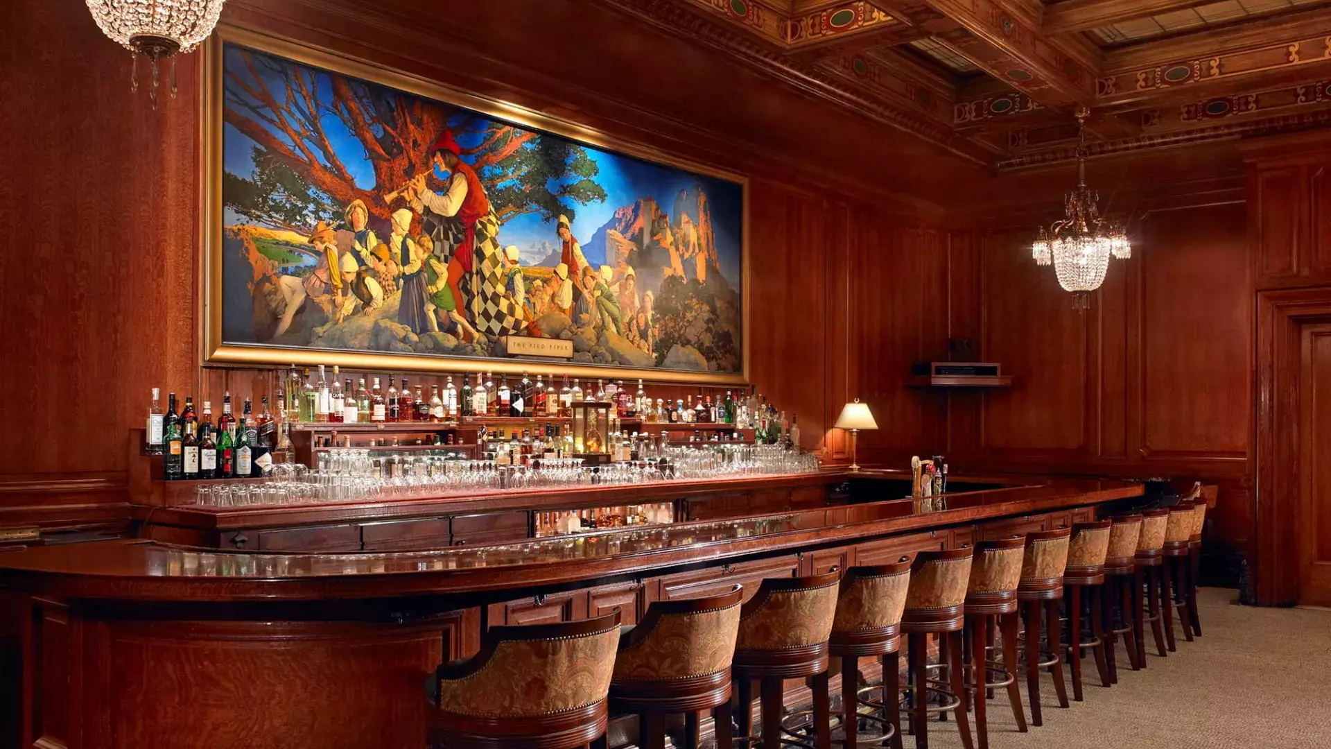 The bar at the Palace Hotel, which features wood-paneled walls and a painting titled The Pied Piper of Hamelin.