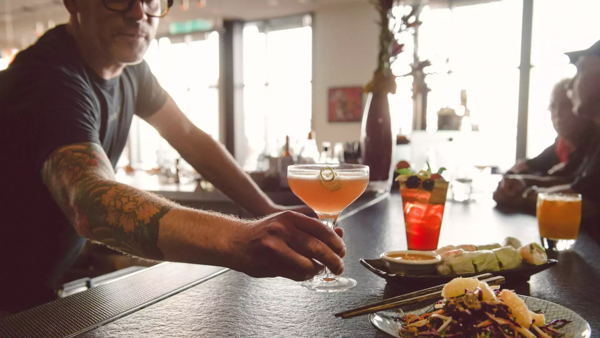 A bartender serves a patron a cocktail at a bar in San Francisco.