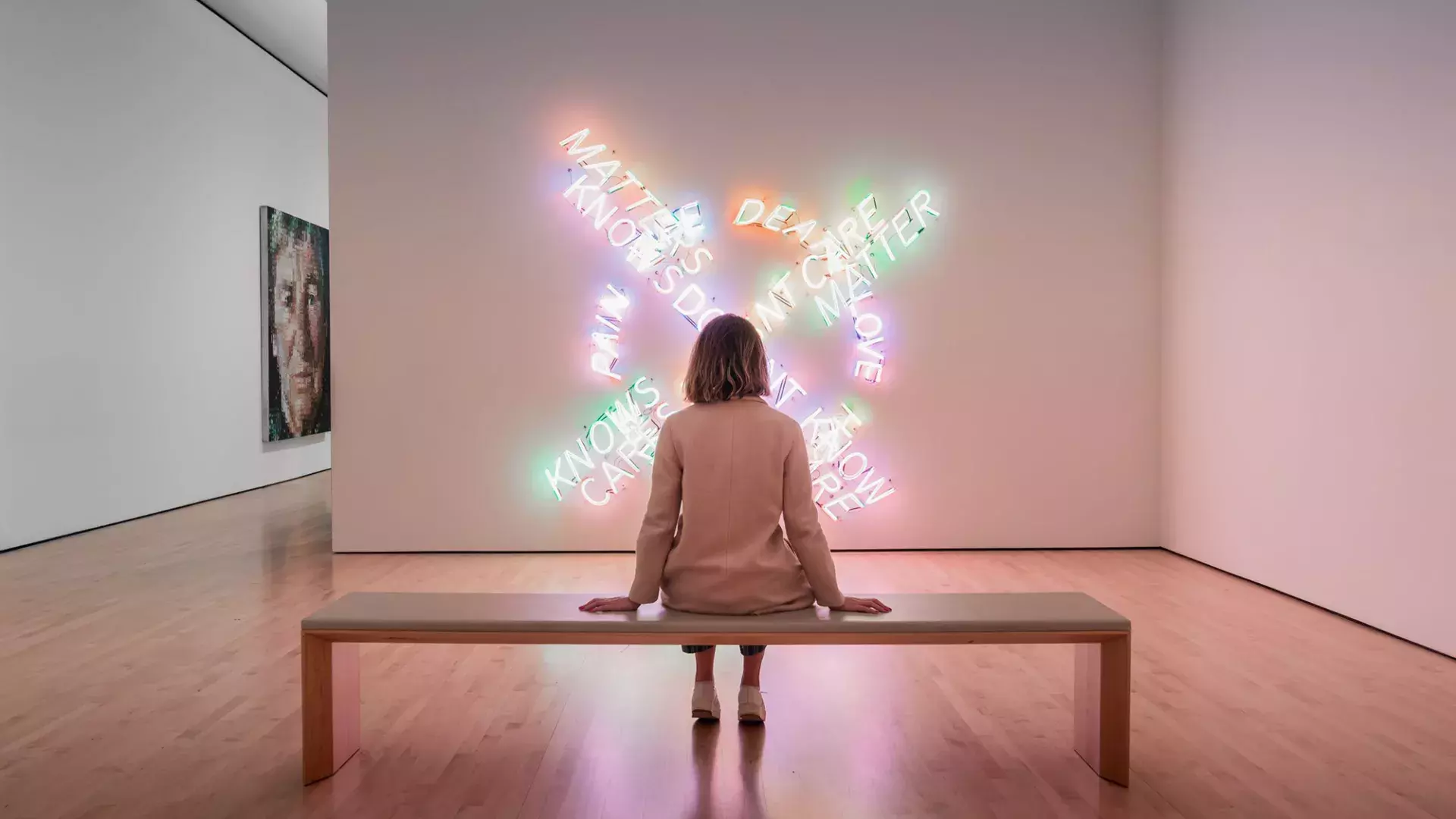 A woman, seated on a bench, looks at a piece of contemporary light art at SF MOMA in San Francisco.