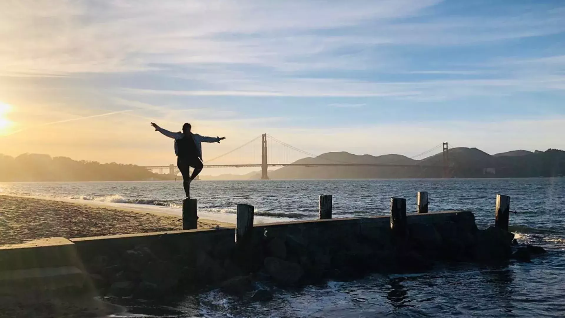 Uma mulher está em um píer no bairro de Marina, em São Francisco, olhando para a Ponte Golden Gate.