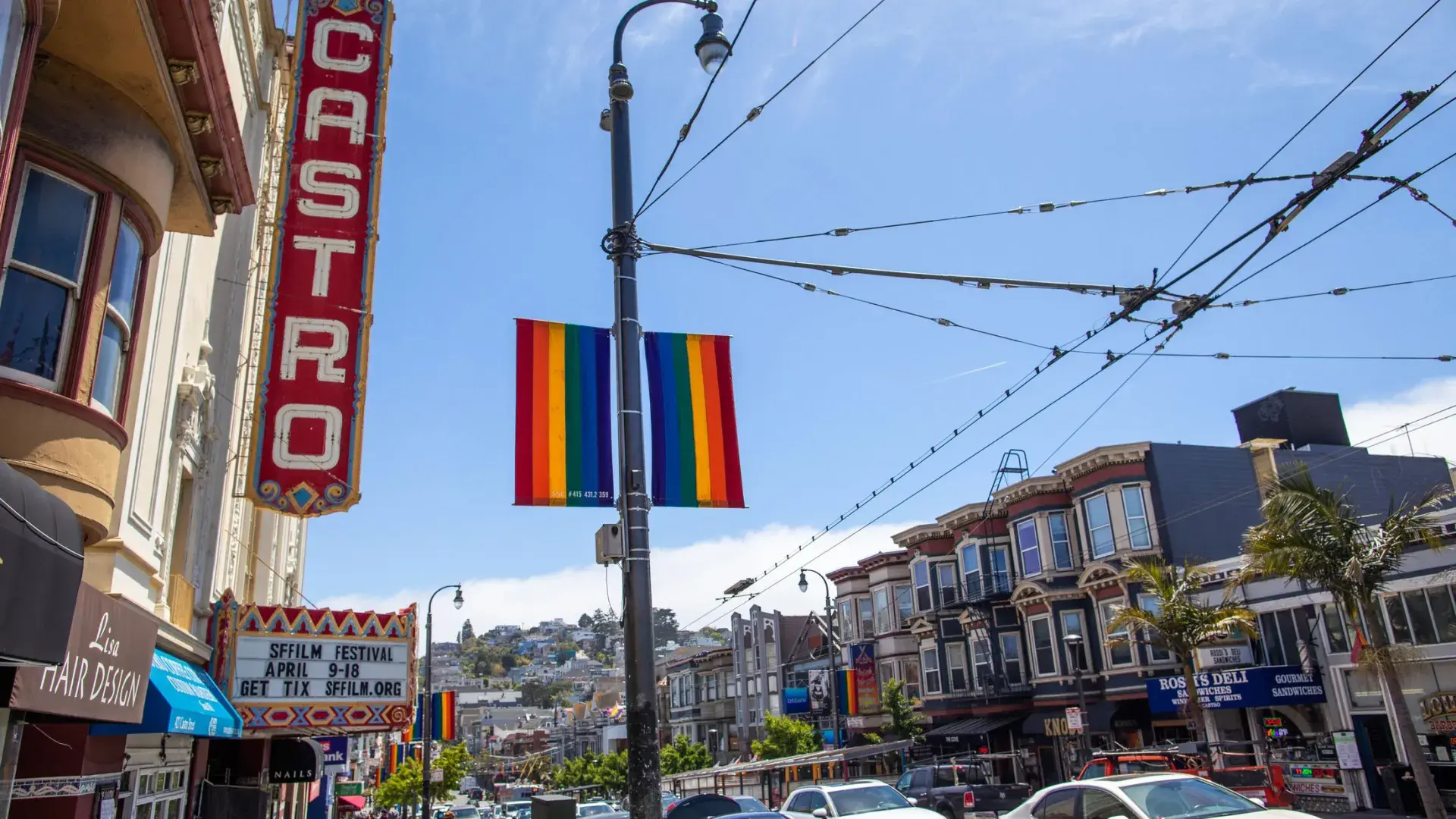 The Castro neighborhood of San Francisco, with the Castro Theater sign and rainbow flags in the foreground.