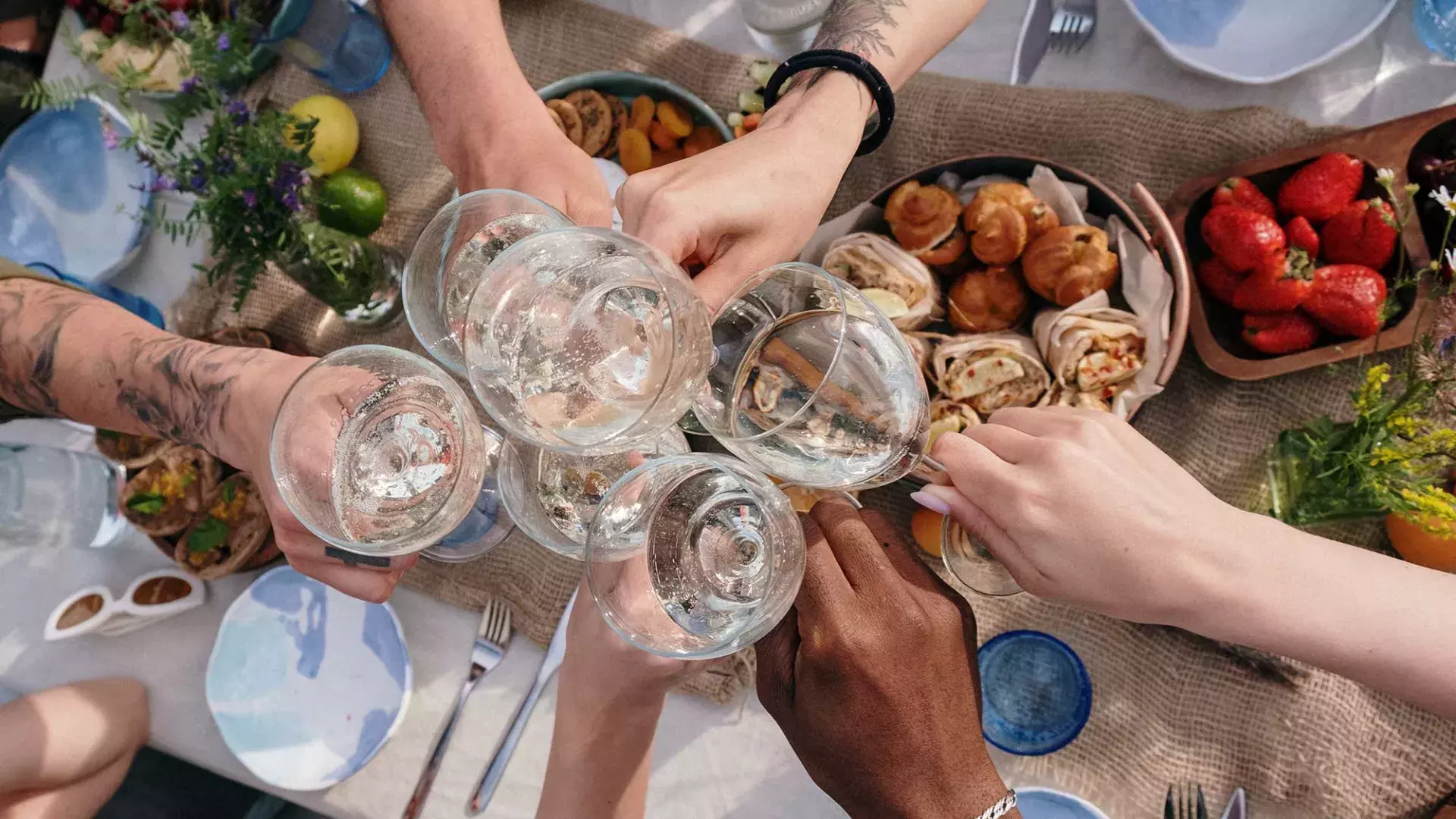 Overhead shot of a group of people clinking glasses at a brunch table.