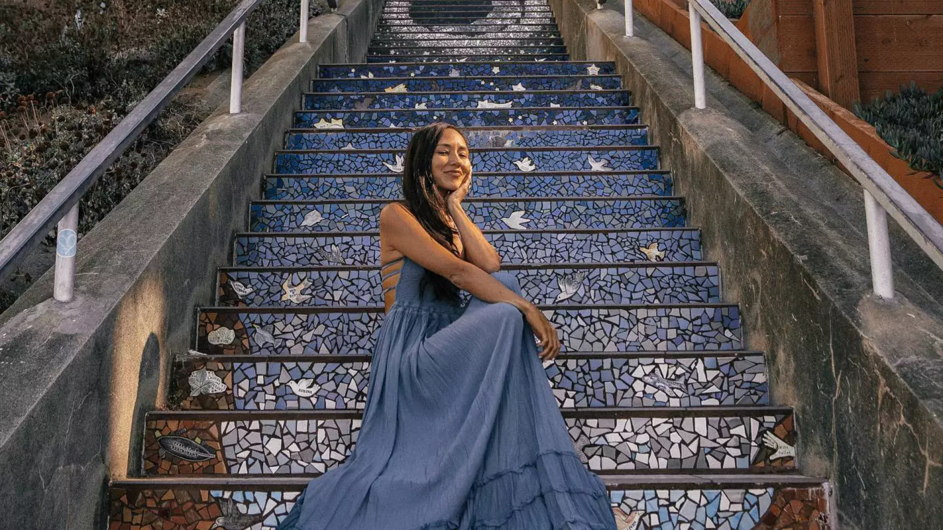 A woman poses sitting on the 16th Avenue tiled stairs in the Sunset neighborhood of San Francisco.