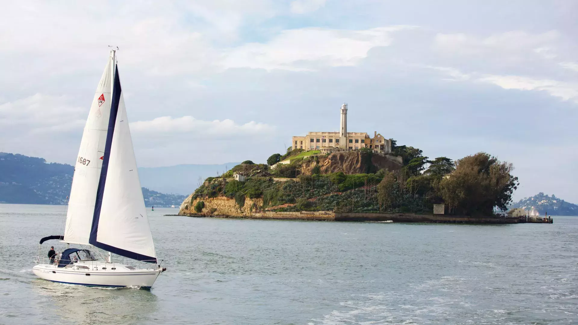 A sailboat passes in front of Alcatraz Island in San Francisco.