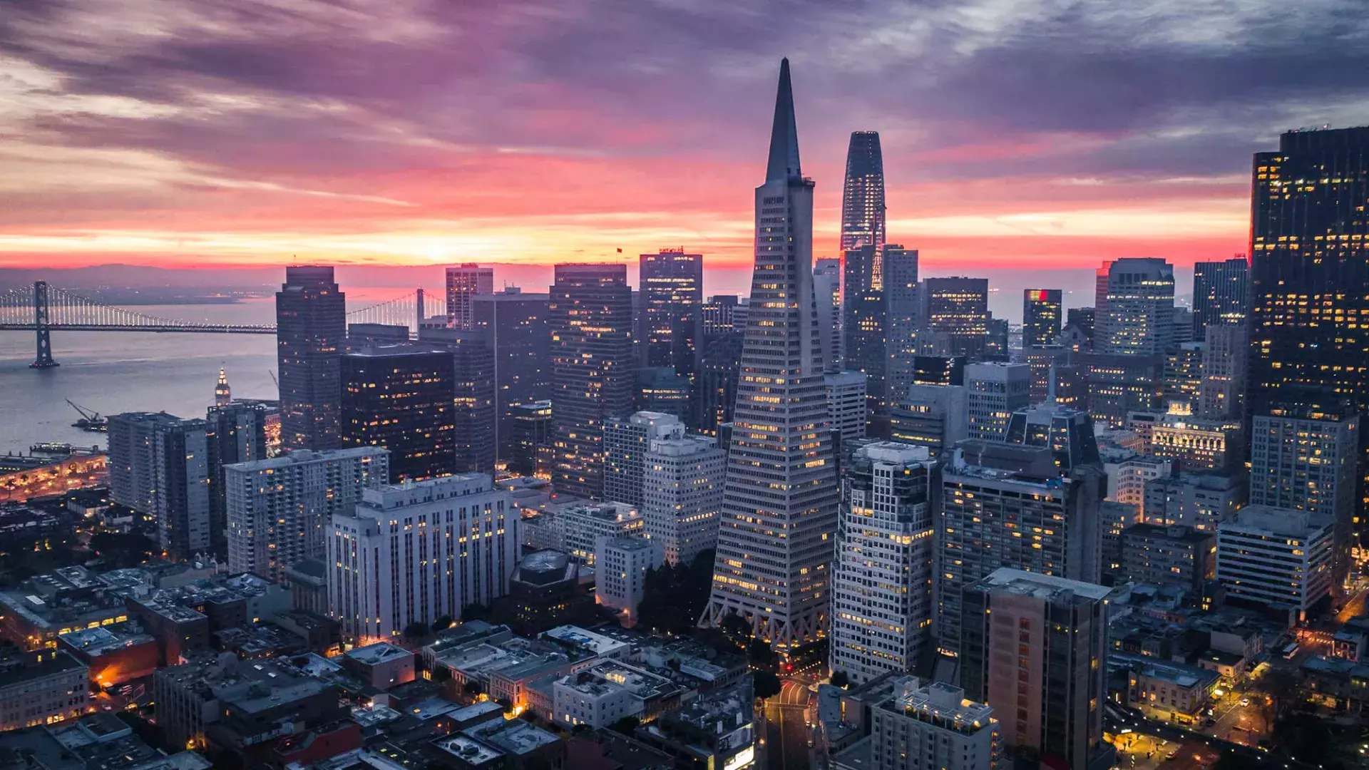 Aerial view of the San Francisco skyline at twilight, with the Transamerica Building and Bay Bridge visible.