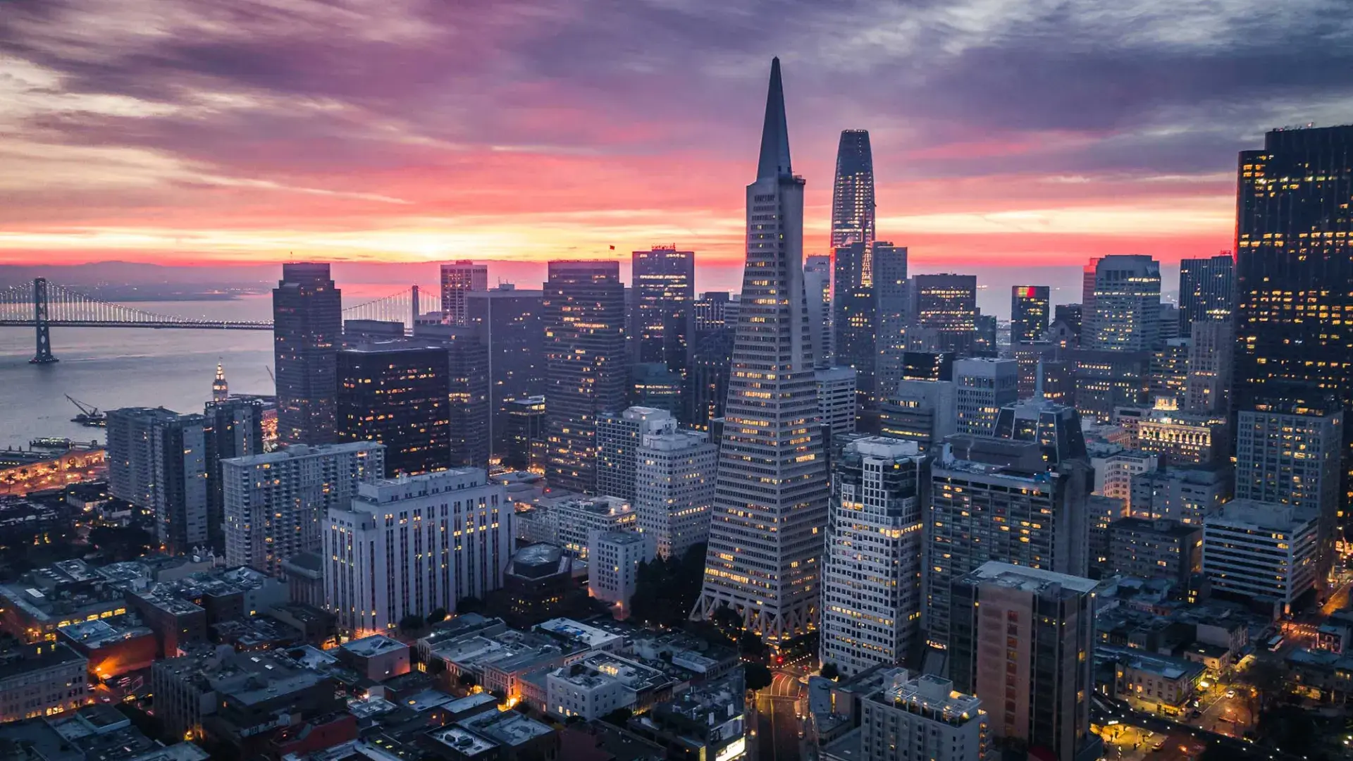 Aerial view of the San Francisco skyline at twilight, with the Transamerica Building and Bay Bridge visible.