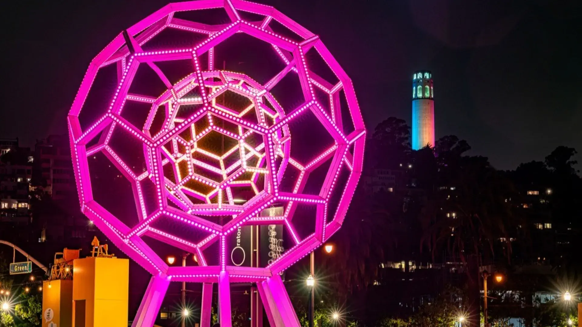 버키볼이 익스플로라토리움 밖에서 빛나고 있으며 배경에는 Coit Tower 보입니다.