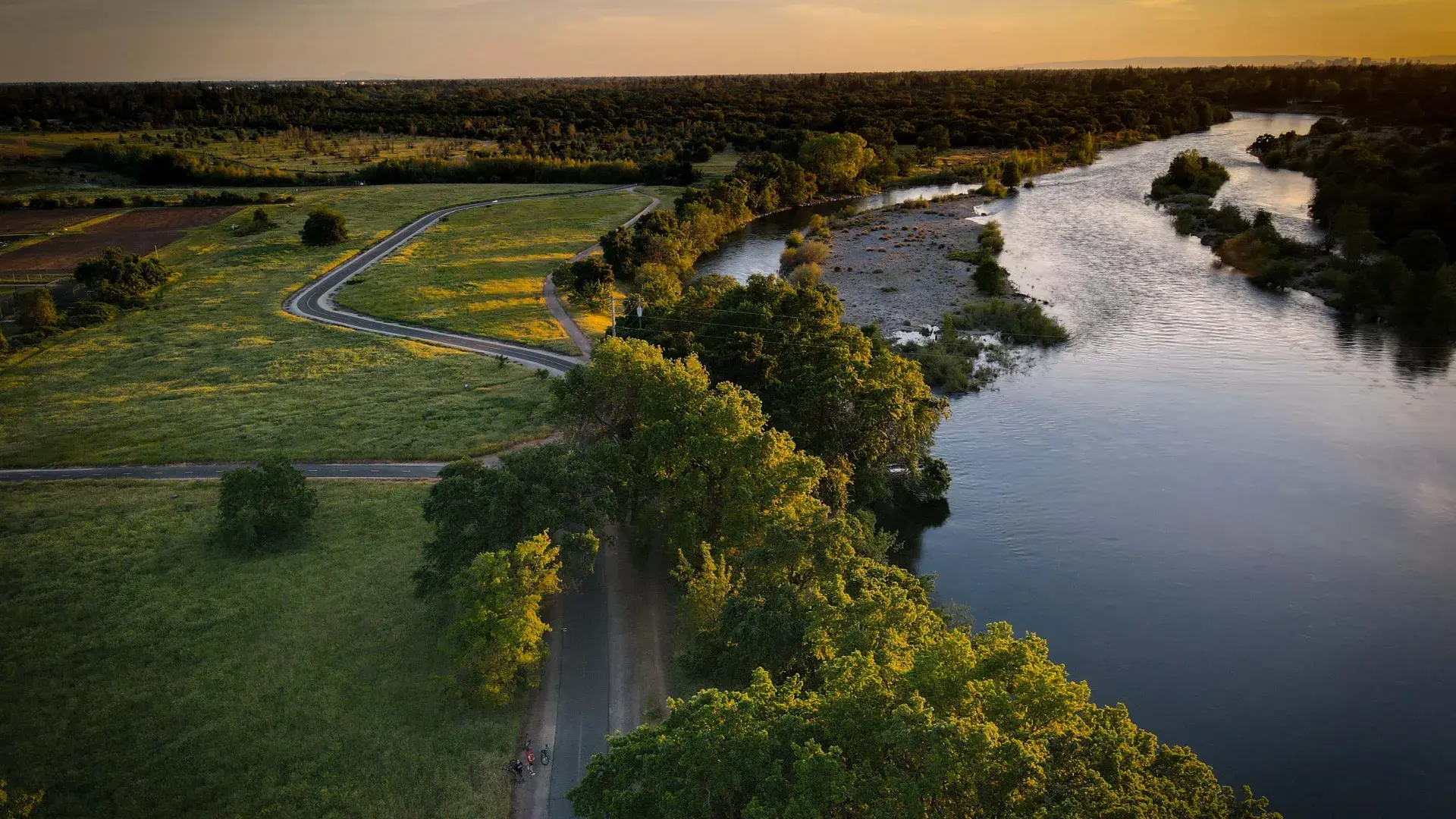 Image of green area and waterway next to it during sun set 