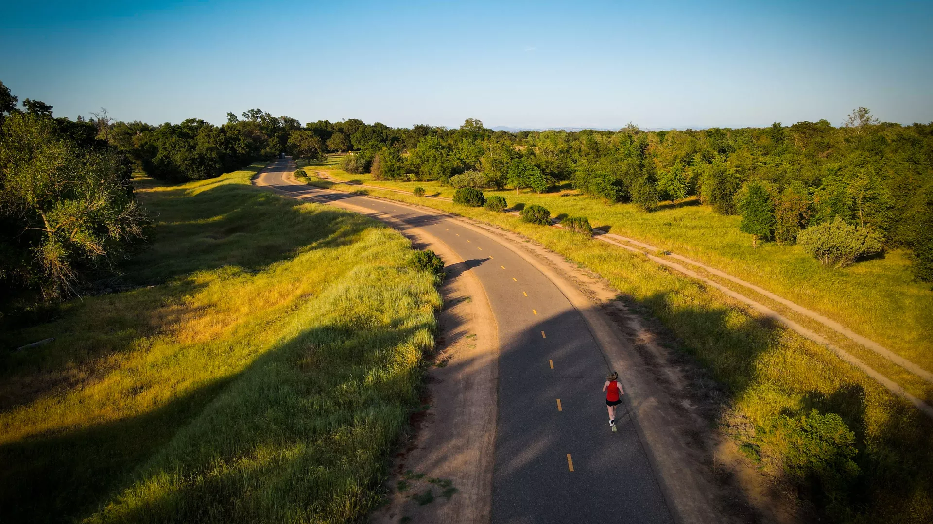 Overhead shot of woman running on a road through the countryside