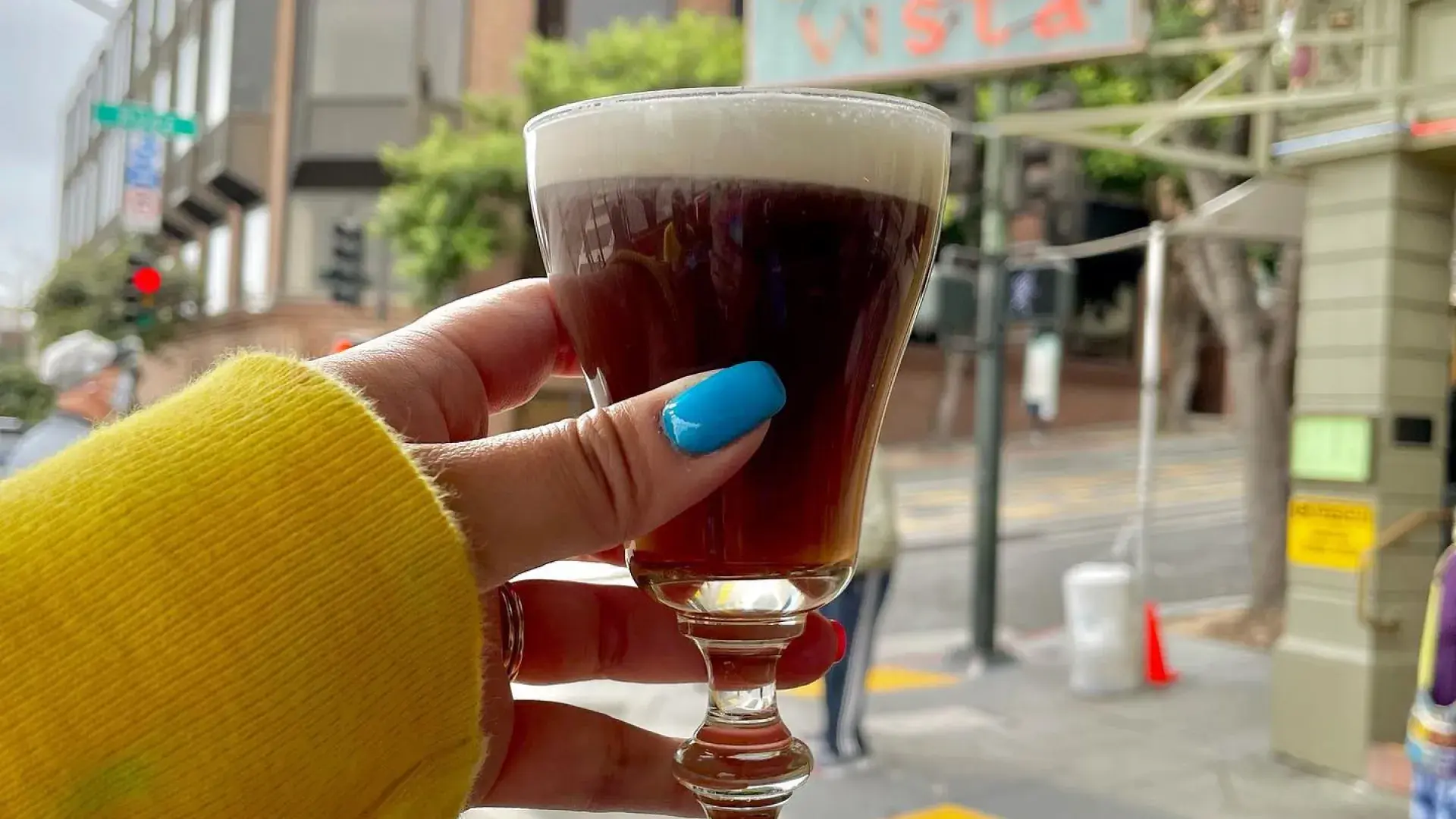 Um visitante saboreia um café irlandês em frente ao famoso Café Buena Vista
