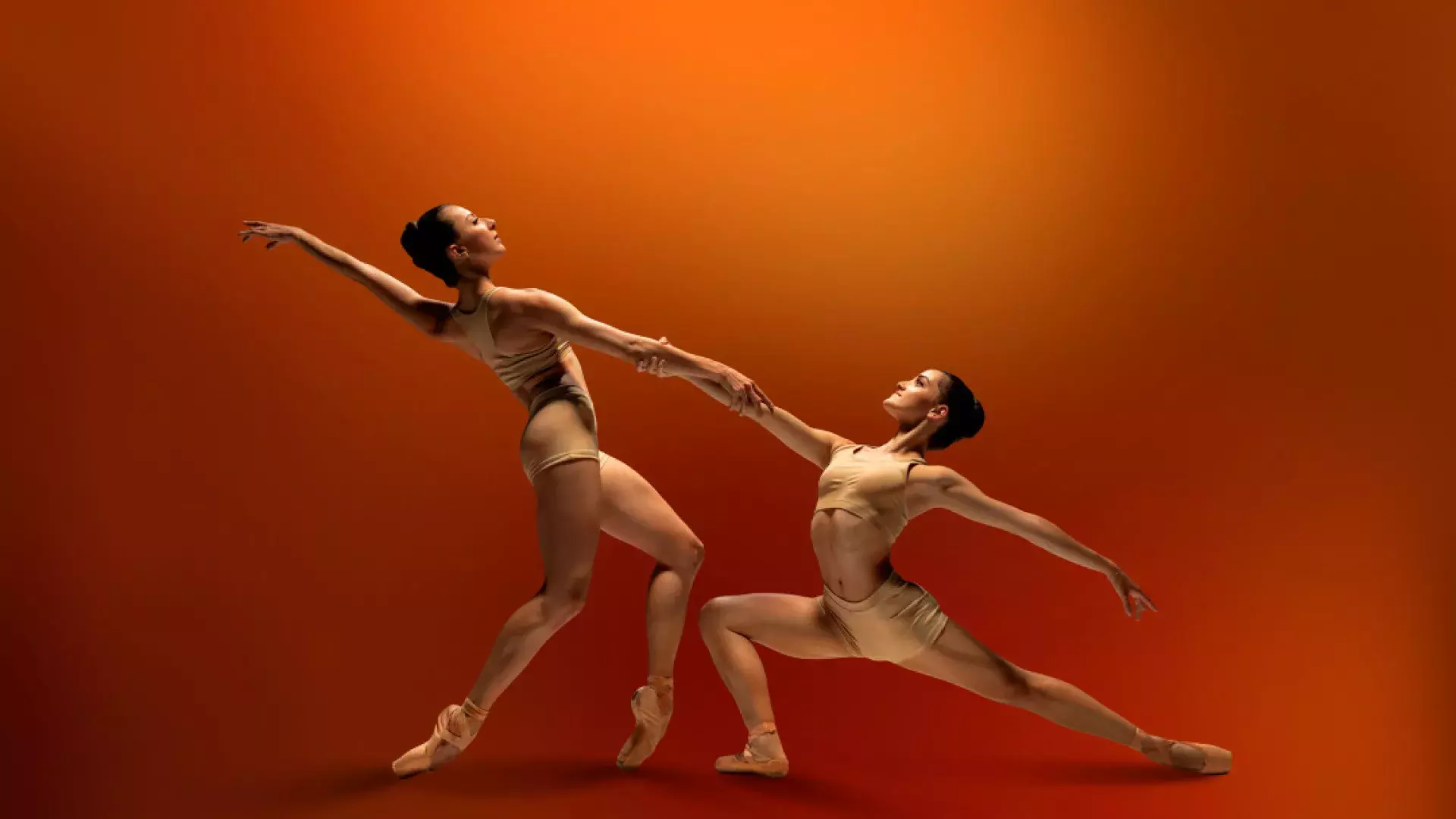 SF ballet dancers holding hands on a red background 