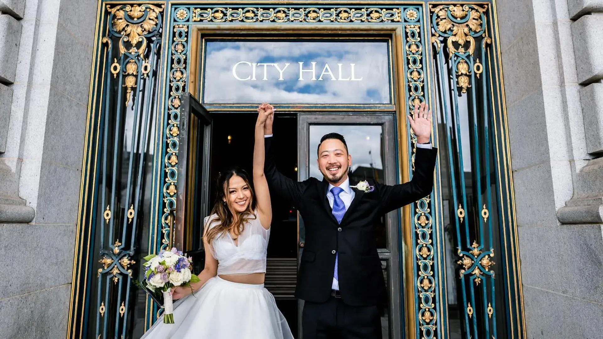 Couple posing in front of city hall after wedding