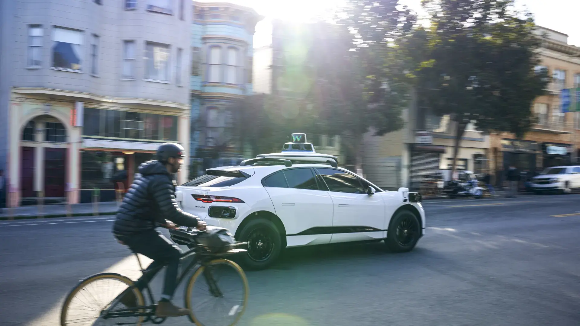 Person riding a bicycle behind a Waymo car