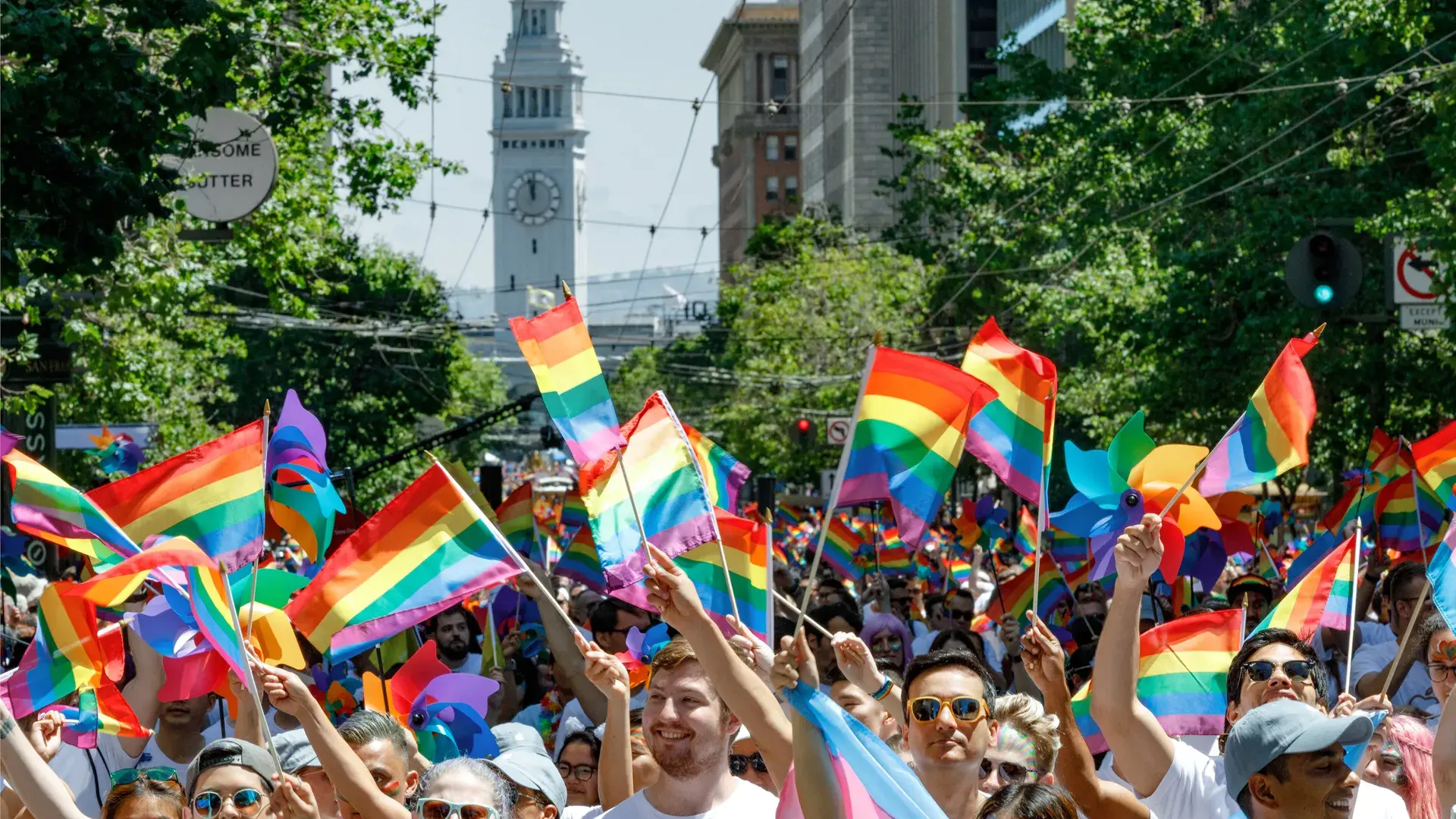 Group holding Pride flags on a sunny day near the San Francisco Ferry Building 