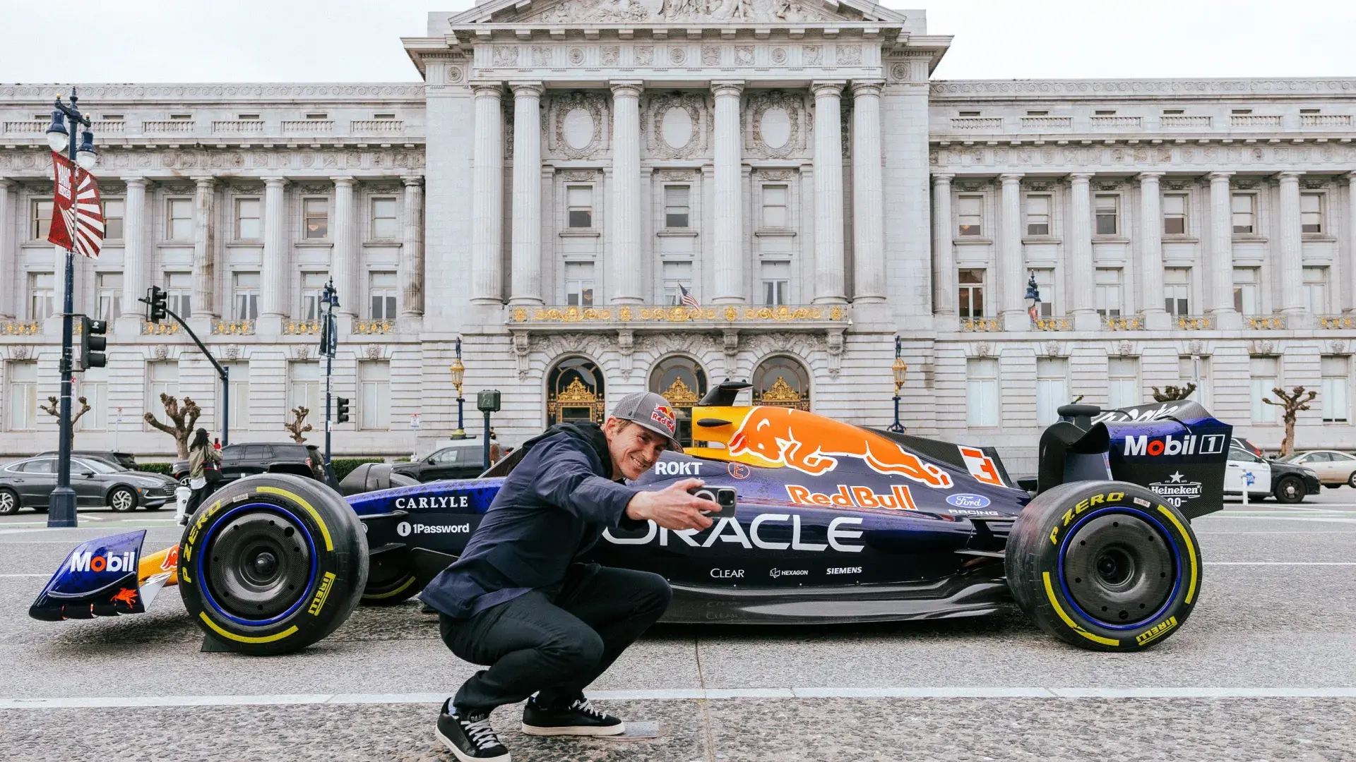 Scott Speed stands in front of a Red Bull Racing F1 car outside San Francisco City Hall.