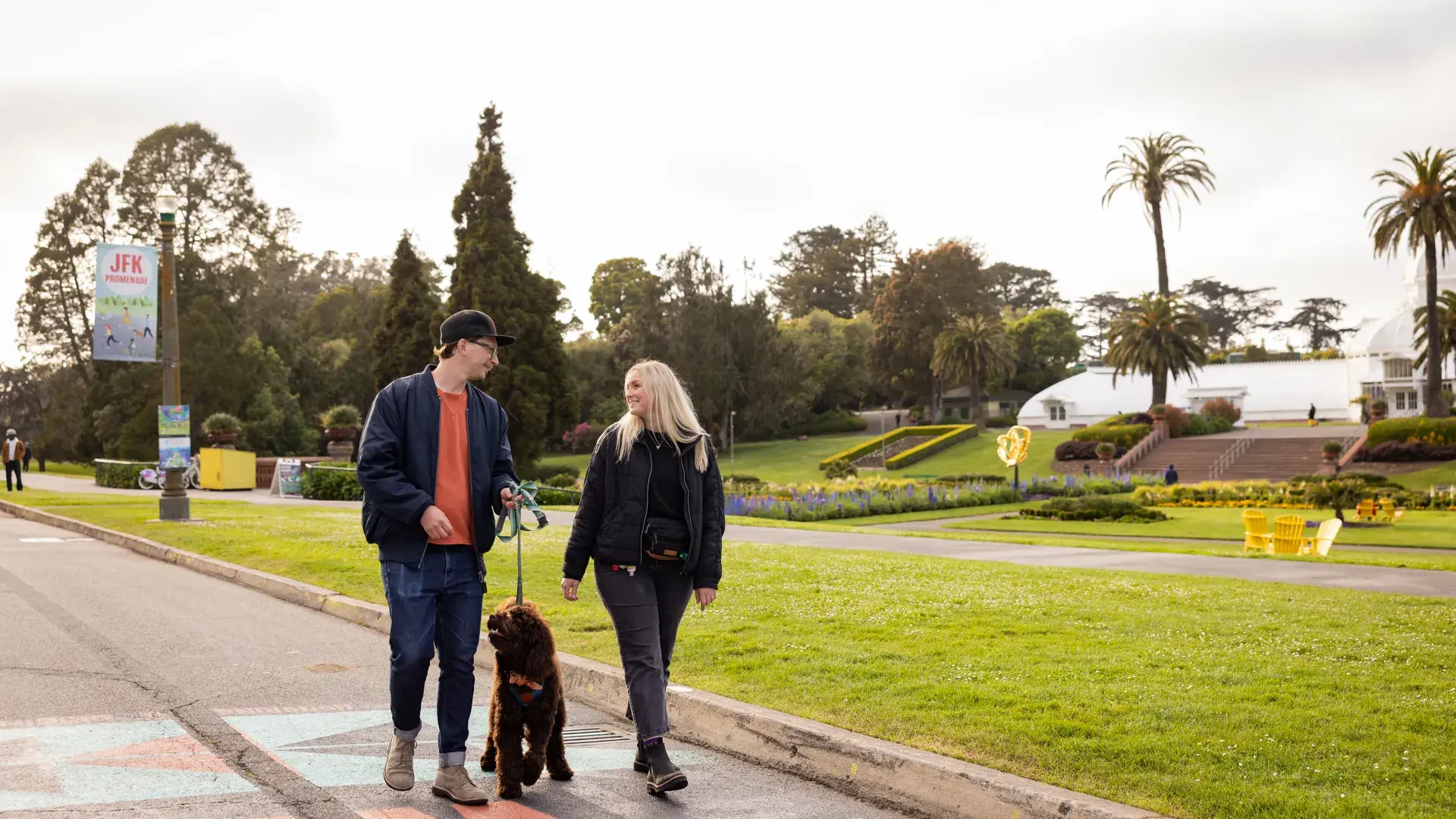 Woman and man walking a dog down JFK in Golden Gate Park