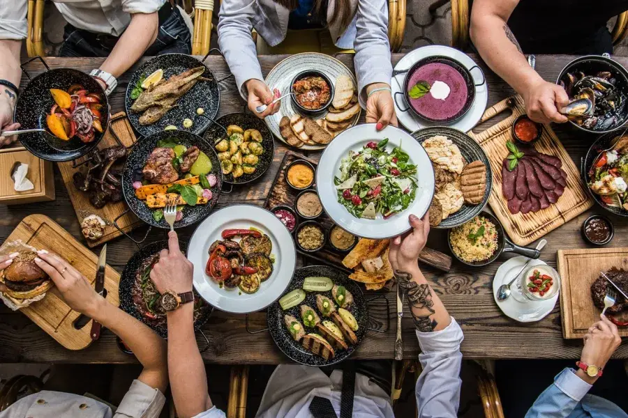 People sitting at a dining table, sharing food.