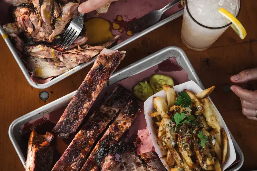 Overhead shot of two plates filled with barbecued meats and sides.