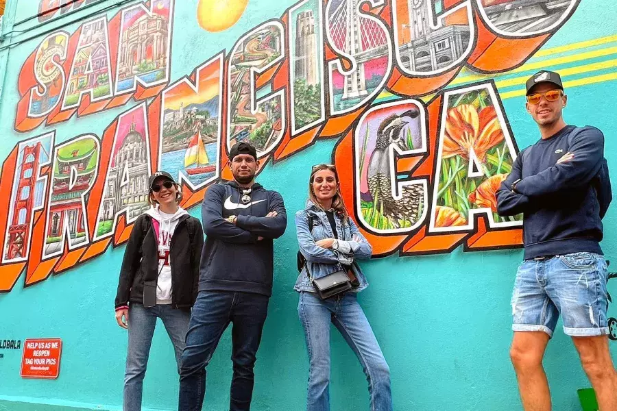 Visitantes da moda posam em frente a um mural de São Francisco.