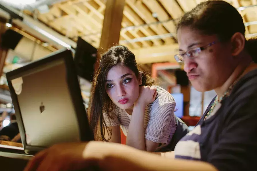 Ayman Nadeem looking over her coworker's shoulder.