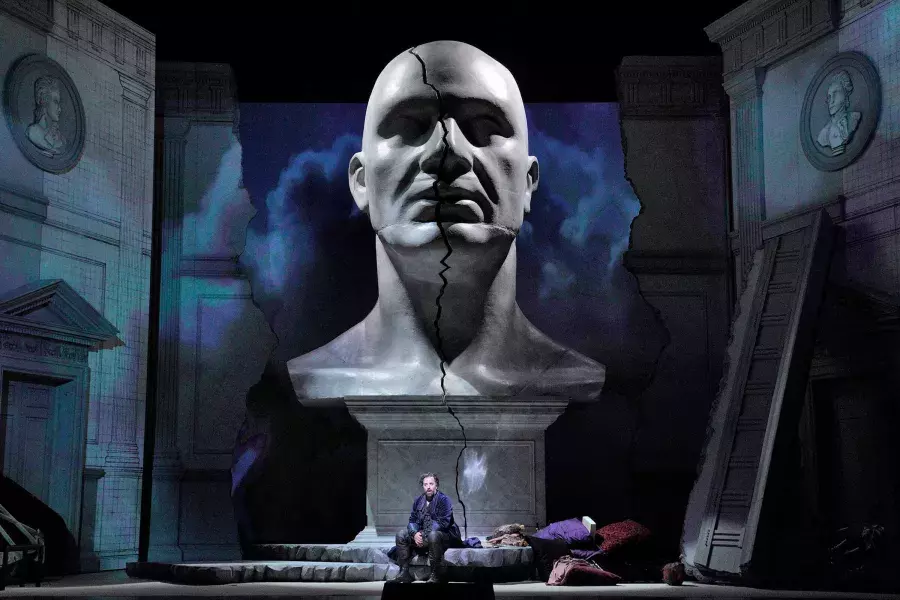 A giant bust of a man looms over two actors on stage in a production of Don Giovanni in San Francisco.