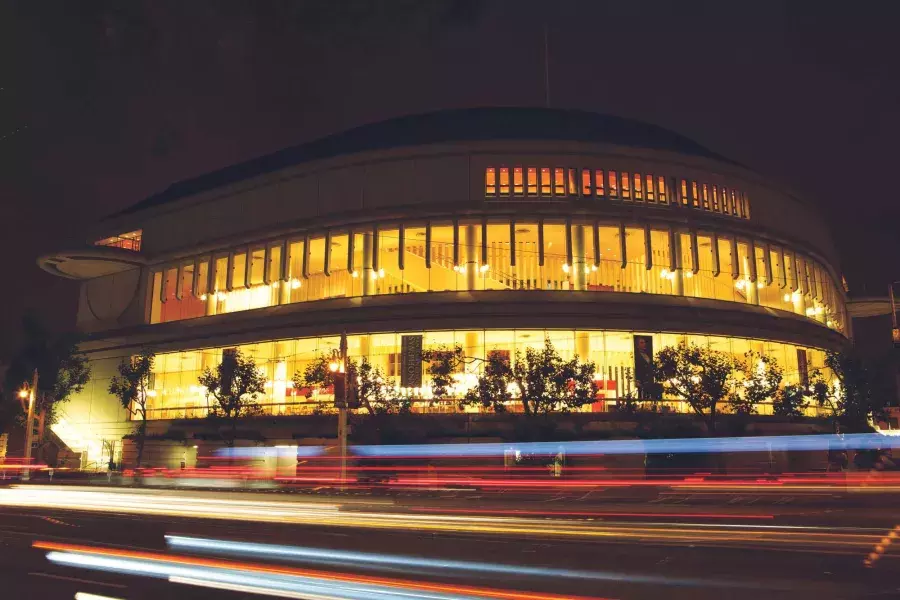 Exterior do Louise M. Davies Symphony Hall à noite com raios de luz dos veículos que passam.