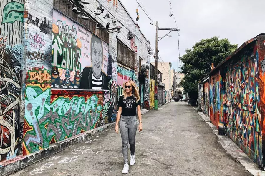 A woman walks through an alley in the Mission District that is covered with murals and artwork. San Francisco, California.