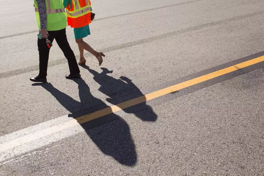 People walking with shadows on a runway.