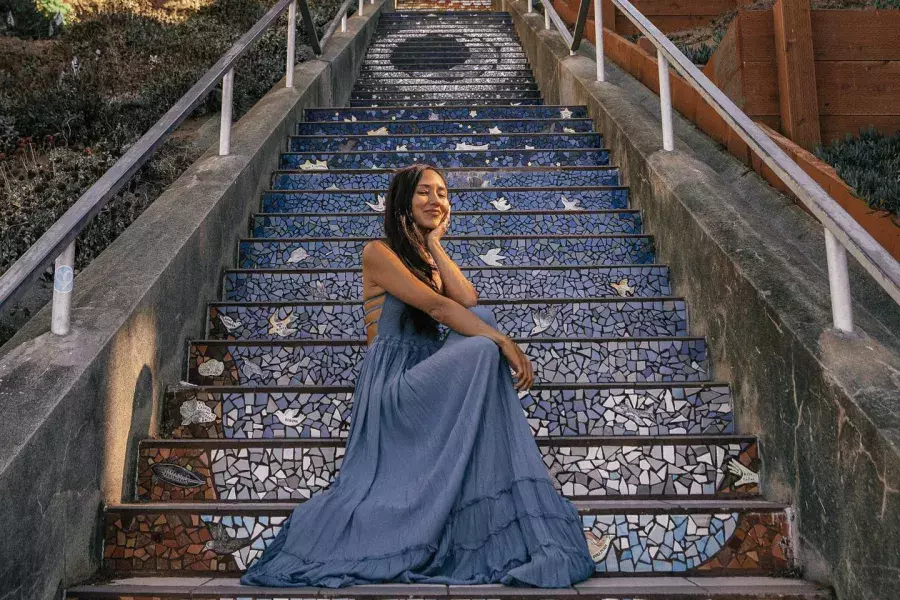 A woman poses sitting on the 16th Avenue tiled stairs in the Sunset neighborhood of San Francisco.