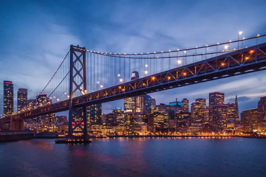 The Bay Bridge and Embarcardero waterfront lit up at night.