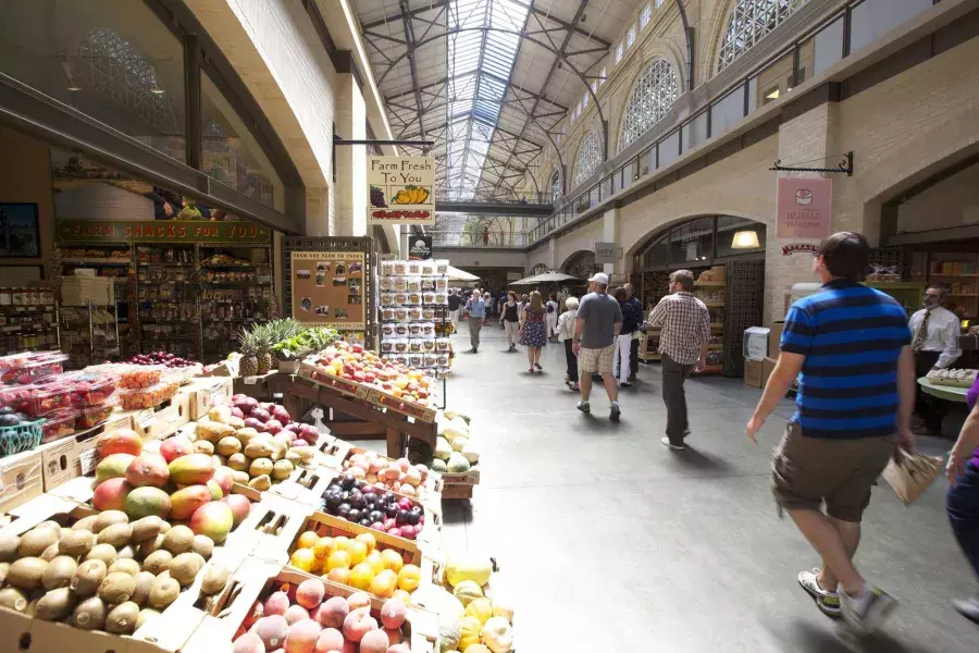 Os compradores caminham pelo Ferry Building Marketplace, com produtos frescos em exposição.