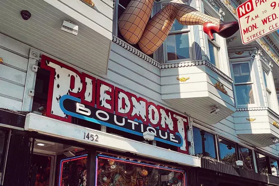 A pair of mannequin legs wearing fishnet stockings hang out of a window over Haight Street at Piedmont Boutique. San Francisco, California.