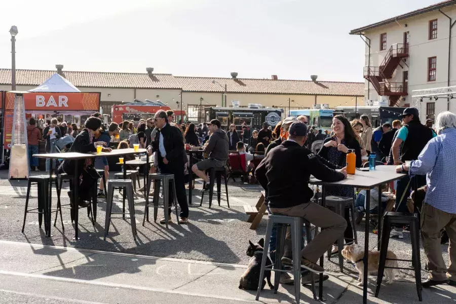 A crowd of people gather to eat at food trucks during Off the Grid at Fort Mason Center.