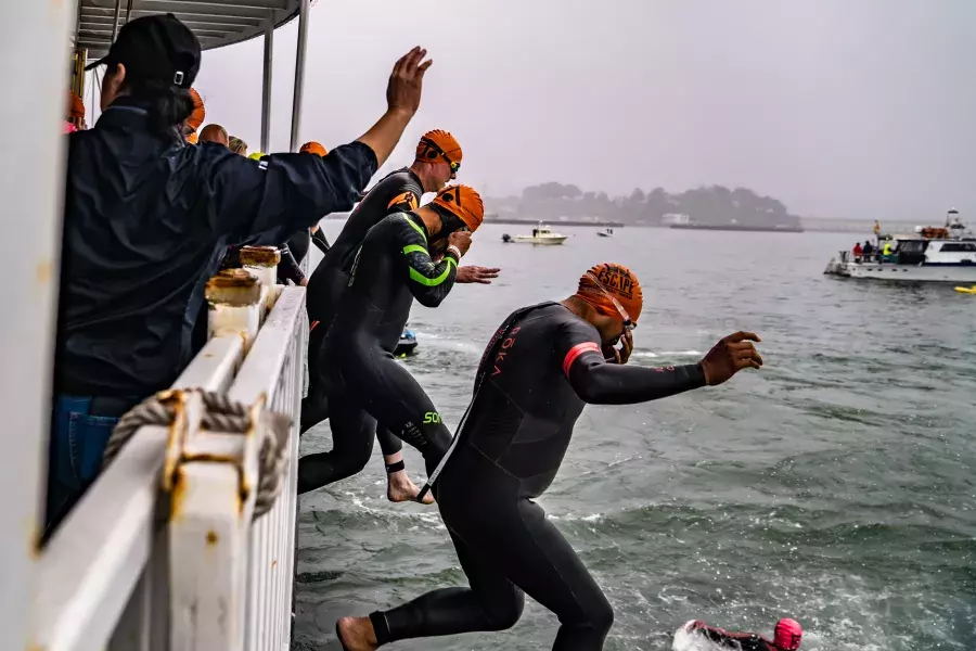 Image of people jumping from boat into San Francisco Bay on a foggy day.