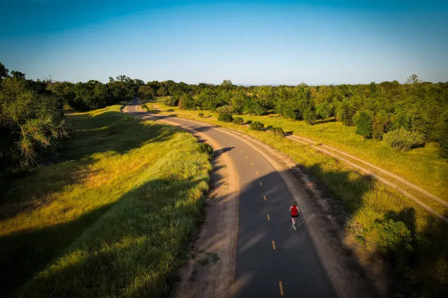 Overhead shot of woman running on a road through the countryside