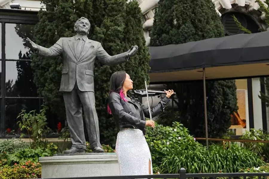 A woman plays the violin in front of the Tony Bennett statue at the Fairmont Hotel.