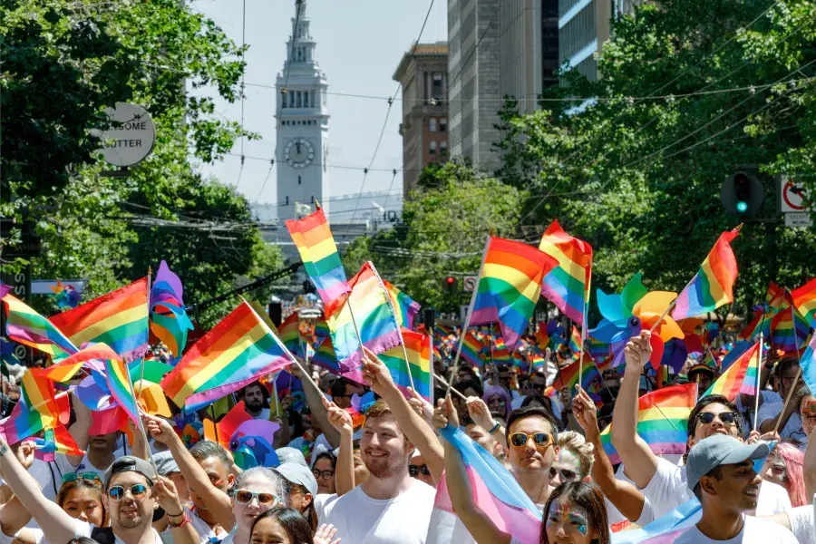 Group holding Pride flags on a sunny day near the San Francisco Ferry Building 
