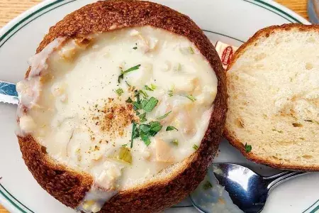 Sopa de mariscos servida em tigela de pão de massa fermentada