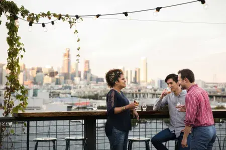 Three people gather around an outdoor table on the roof deck of Anchor Distilling in San Francisco, California.