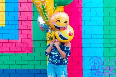 女の子がカラフルな壁画の前で風船で誕生日を祝っています。