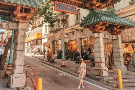 한 여성이 샌프란시스코 Chinatown 입구를 표시하는 화려한 문 앞에서 포즈를 취하고 있다.