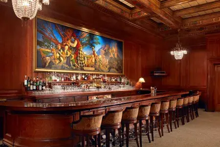 The bar at the Palace Hotel, which features wood-paneled walls and a painting titled The Pied Piper of Hamelin.