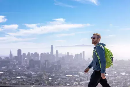 A visitor hikes to the top of Twin Peaks with his backpack.