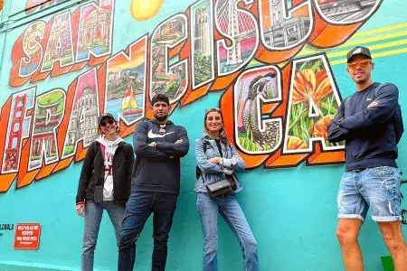Visitantes da moda posam em frente a um mural de São Francisco.