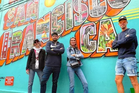 Trendy visitors pose in front of a San Francisco mural.